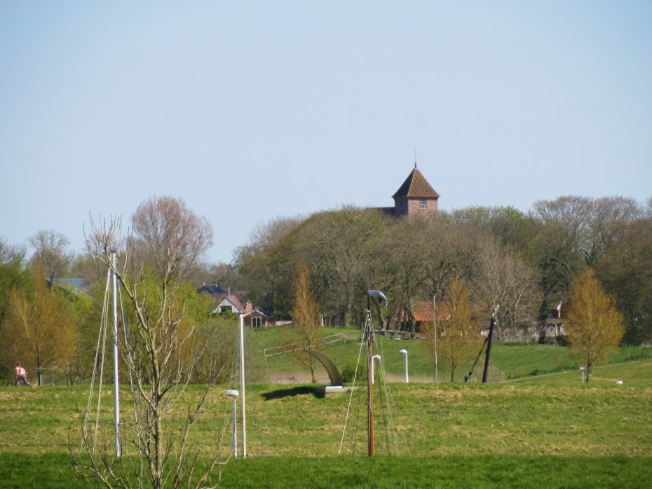 Ter kerkje van Termunten gezien vanaf Termunterzijl; op de voorgrond de masten van bootjes.